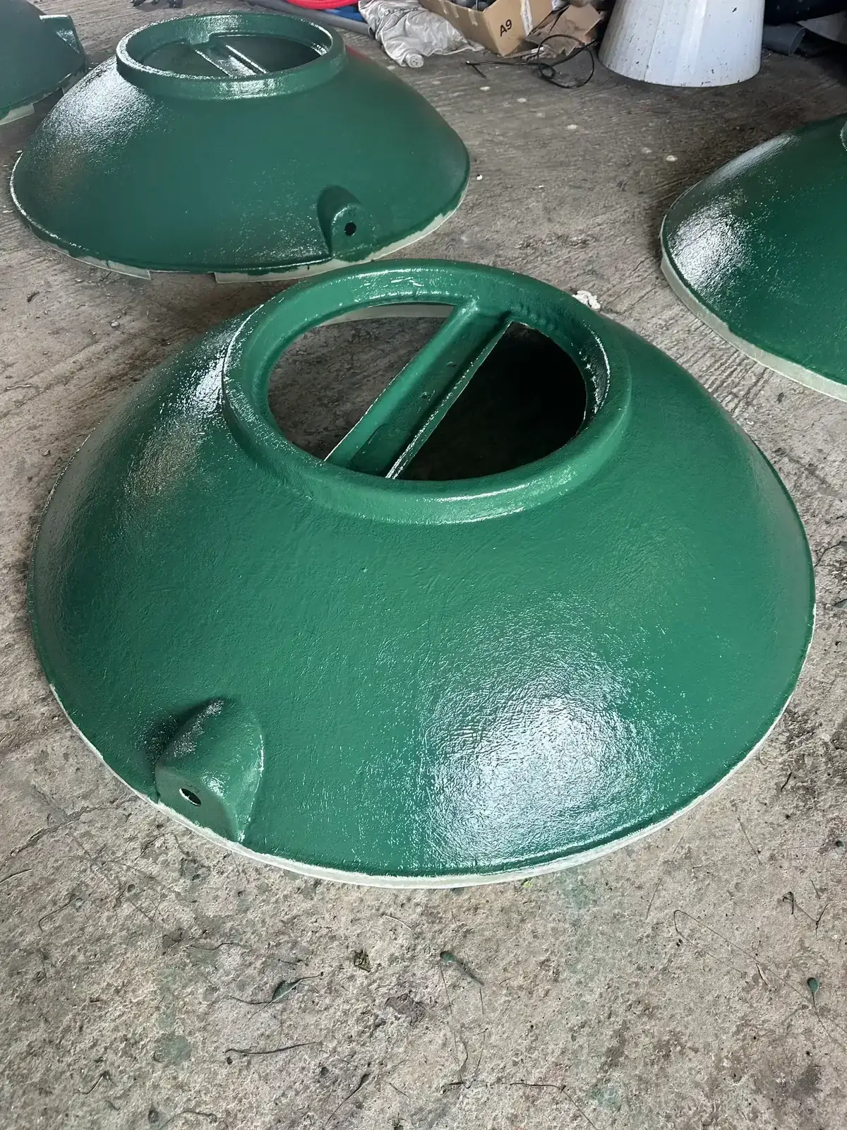 Dômes de cuve fraîchement recouverts de gelcoat vert brillant, posés au sol de l'atelier