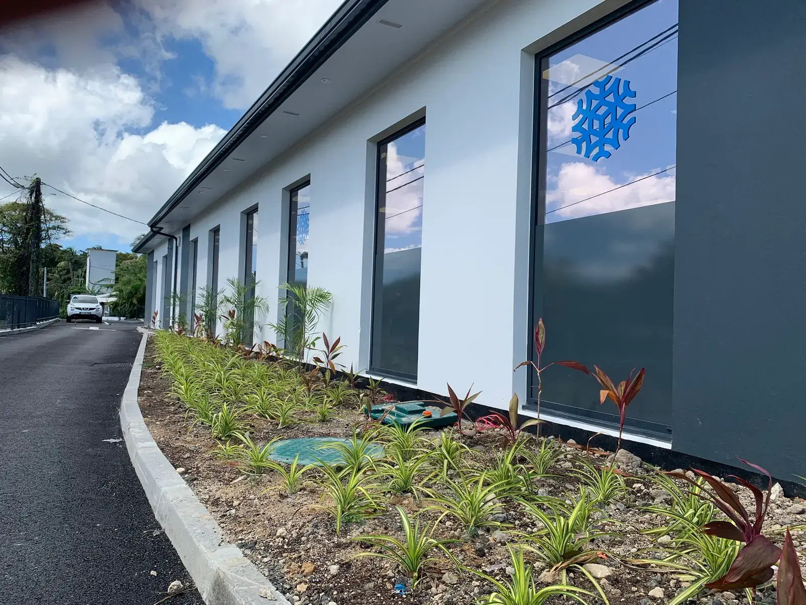 Local commercial neuf en Martinique : dans le massif planté le long de la façade, les tampons verts d'une micro-station Diamond 5 EH posée par Asseco