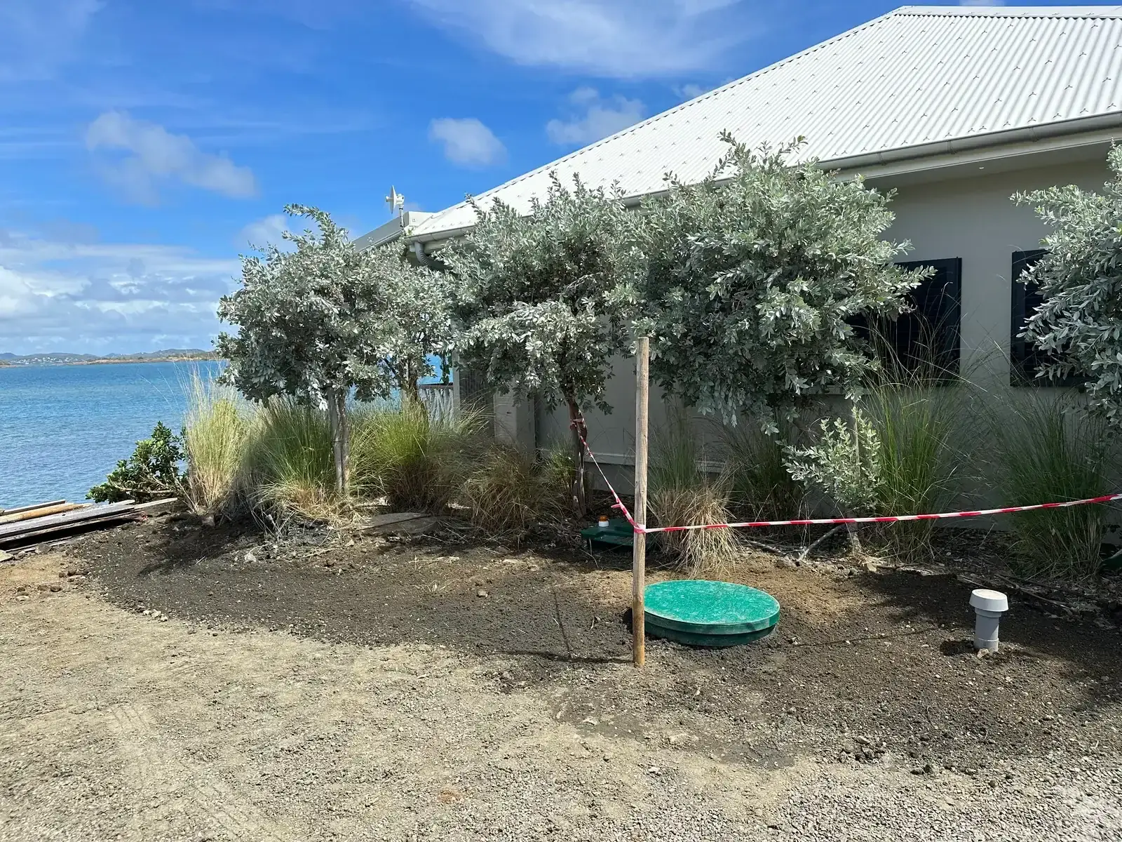 Le même jardin face à la mer, terre nivelée et plantée, le couvercle vert de la cuve affleurant au sol