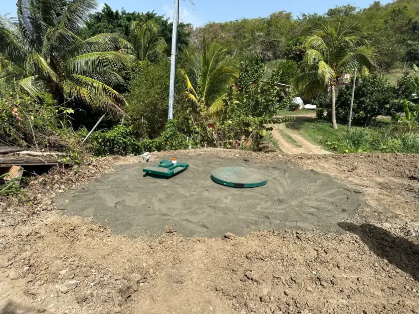 Deux couvercles verts sur un lit de sable fraîchement nivelé, au milieu des cocotiers