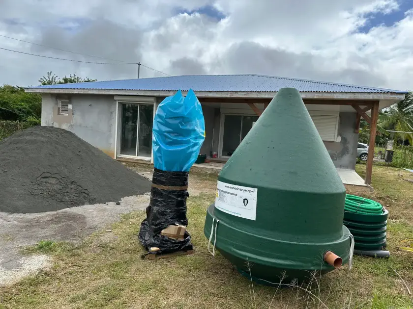 Une micro-station Diamond livrée devant une maison, à côté d'un tas de sable et de tuyaux