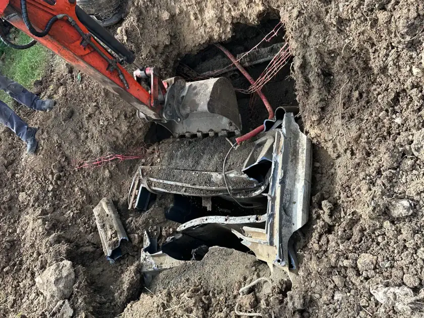 Au fond de la fouille, le godet de la mini-pelle dégage des débris de béton et de plastique