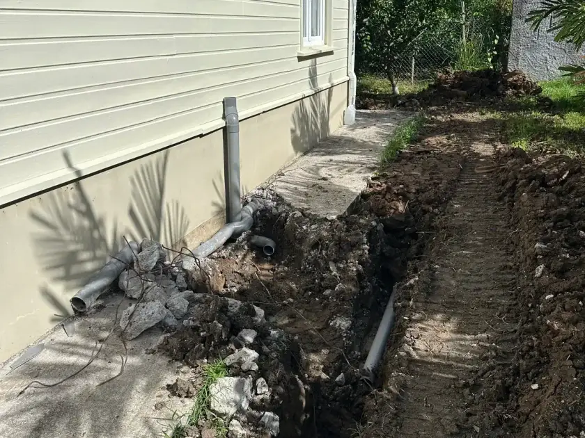 Tranchée ouverte le long d'une maison en bardage, tuyaux d'évacuation raccordés vers la nouvelle installation